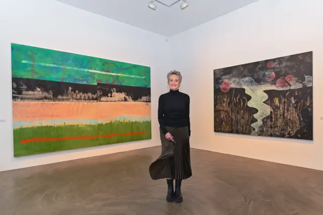 Sharon Stone na frente de dois quadros enormes em galeria de arte em Berlim