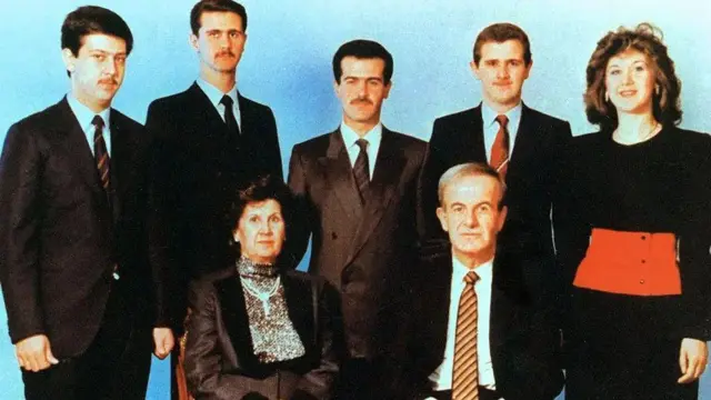 Syrian President Hafez al-Assad and his wife Anisa pose with their children (from left to right) Maher, Bashar, Bassel, Majd and Bushra for a photograph taken around 1990. All Assad men are wearing dark suits, light shirts and ties while both women wear long-sleeved dresses.