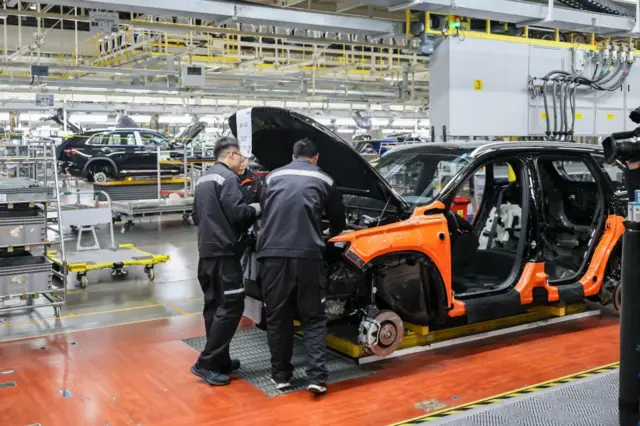 Des employés travaillent sur la ligne d'assemblage du véhicule électrique Smart dans la base de production automobile de Geely, le 12 décembre 2024 à Xi'an, dans la province de Shaanxi, en Chine.