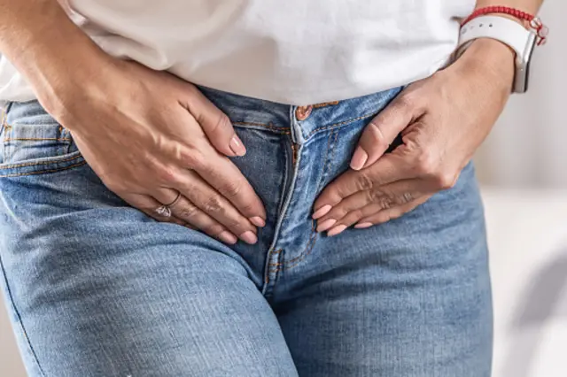 Femme avec ses mains au bas ventre