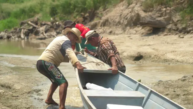 Oliveira e amigos arrastando canoa 