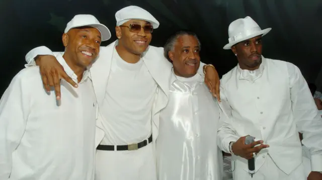 Sean 'Diddy' Combs posando para foto com o produtor musical Russell Simmons, o rapper LL Cool J e o reverendo Al Sharpton. Todos estão vestidos de branco