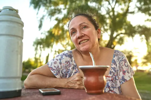 Mulher sorrindo ao lado de cuia de chimarrão