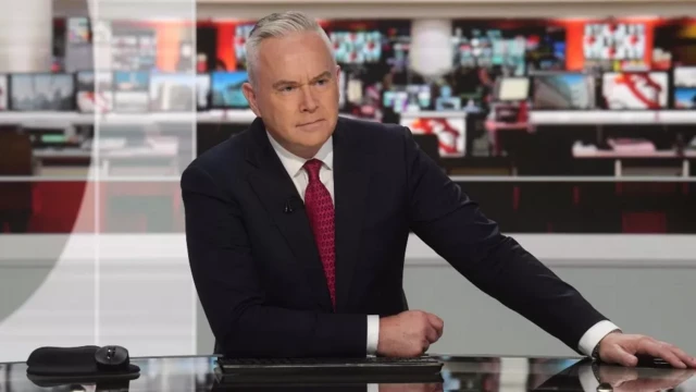 Huw Edwards sentado em bancada da BBC