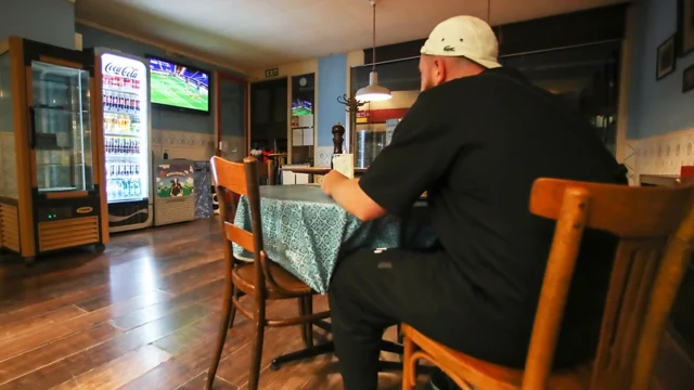 Homem em restaurante almoçando enquanto assiste à TV