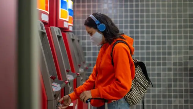 Jovem de máscara mexe em caixa eletrônico 24 horas