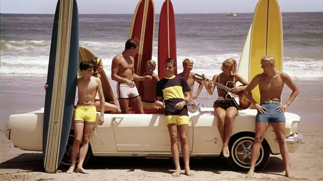 Fotografia de grupo de jovens brancos com pranchas de surfe em uma praia