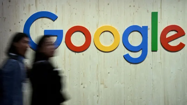 Vultos de pessoas caminhando em frente a parede com logo do Google