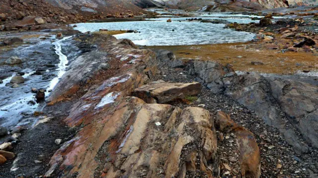 Rochas ao redor de um lago de água clara, fruto do gelo que derreteu.