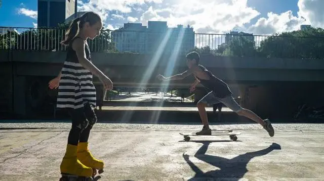 Crianças brincando na rua com skate e patins