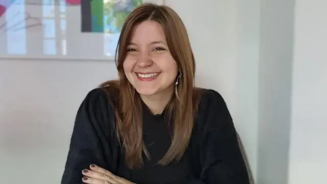 Amanda Marton sorrindo para foto em sala