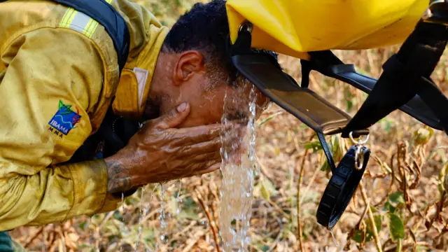 Brigadista toma água em meio a combate a incêndios