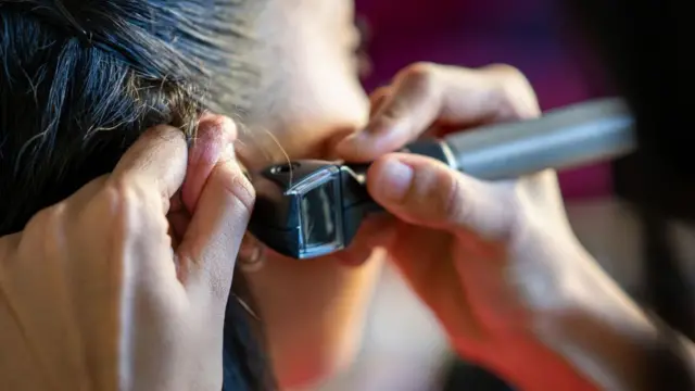 Médico usando um otoscópio para examinar ouvido de paciente