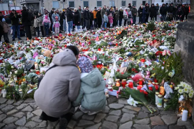 Pessoas deixando flores em homenagem às vítimas