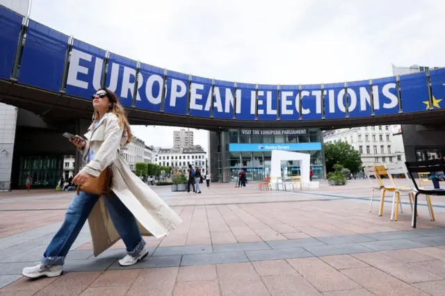 Uma mulher passando por um cartaz das eleições europeias.