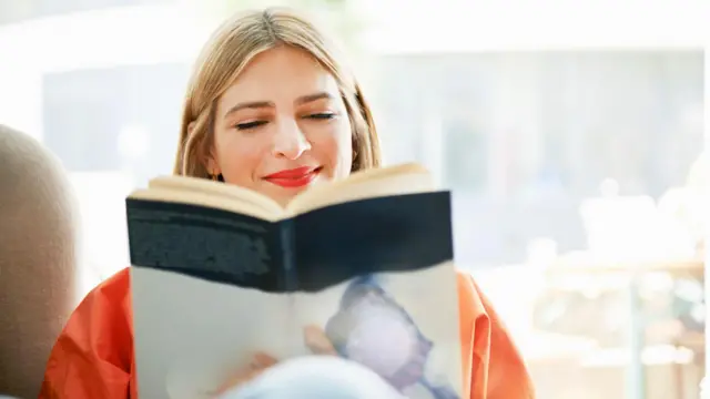 Mulher sorrindo lendo um livro