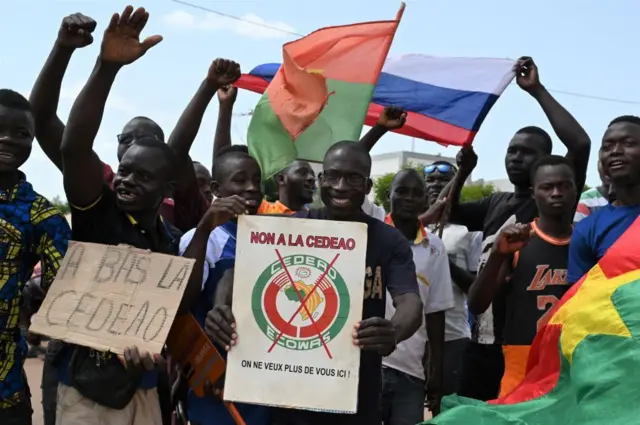 Un petit groupe de manifestants brandit des drapeaux russes et burkinabés pour protester contre la Communauté économique des États de l'Afrique de l'Ouest (CEDEAO), dont les représentants sont attendus aujourd'hui à Ouagadougou, le 4 octobre 2022. 