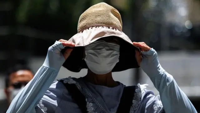 Mulher se protege do sol na China com um chapéu