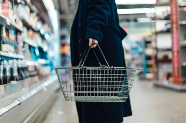 Pessoa segurando cesta em supermercado