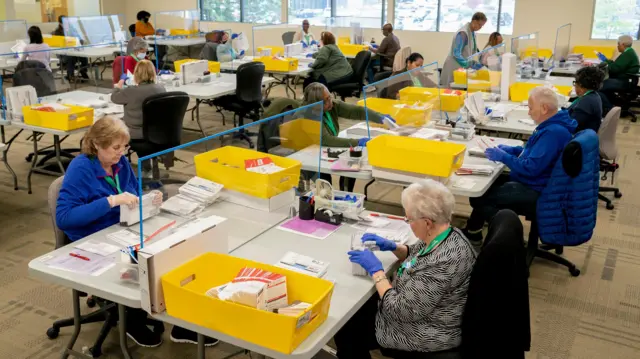 Os trabalhadores eleitorais organizam a contagem das cédulas na sede da King County Elections em Renton, Washington, EUA.