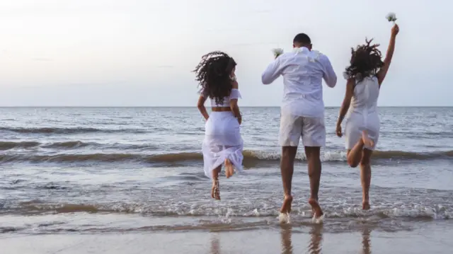 Pessoas pulando onda na praia vestidos de branco