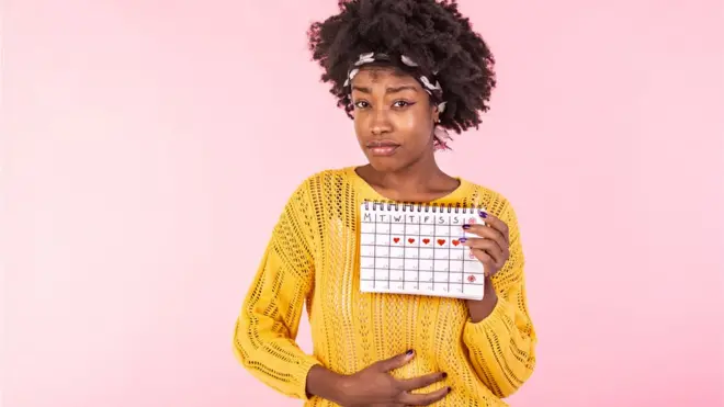 Une jeune femme qui tient un calendrie pour ses règles