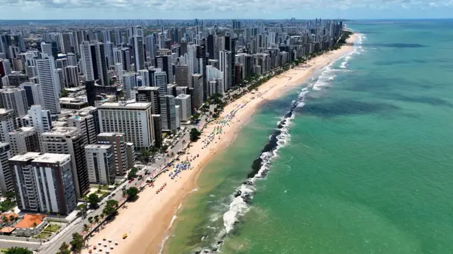 Foto aérea mostra prédios e praia em Recife