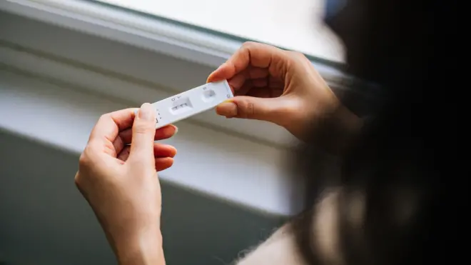 Mulher olhando resultado de teste rápido de covid-19