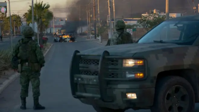 Carro da polícia em frente à veículo incendiado