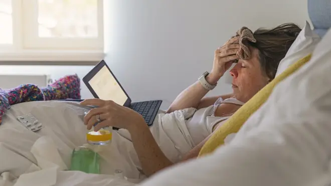 Mujer en la cama con dolor de cabeza