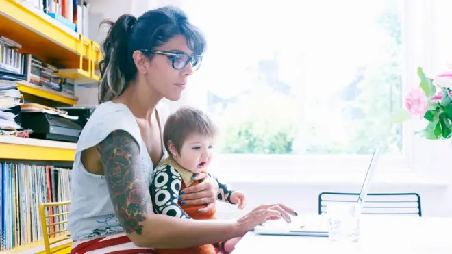 Mulher trabalhando com bebê no colo