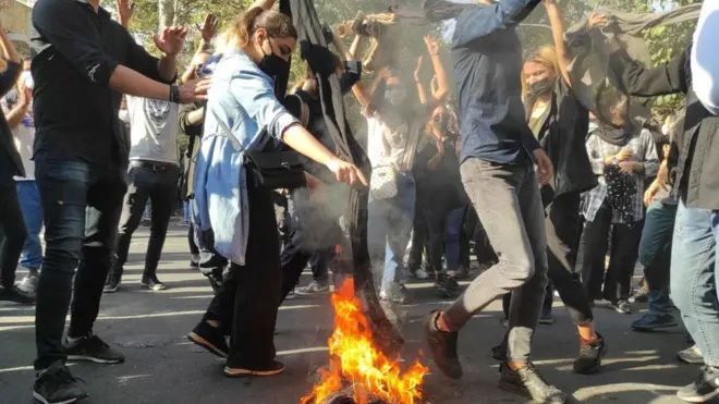 A woman burns her headscarf on a bonfire at a protest in Tehran, Iran (1 October 2022)