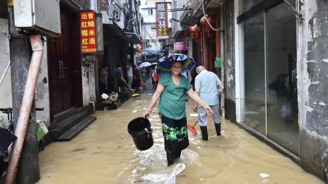 福建建甌，一名婦女行過被洪水淹沒的街道