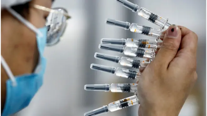 A worker performs a quality check in the packaging facility of Chinese vaccine maker Sinovac Biotech, developing an experimental coronavirus disease (COVID-19) vaccine, during a government-organized media tour in Beijing, China, September 24,