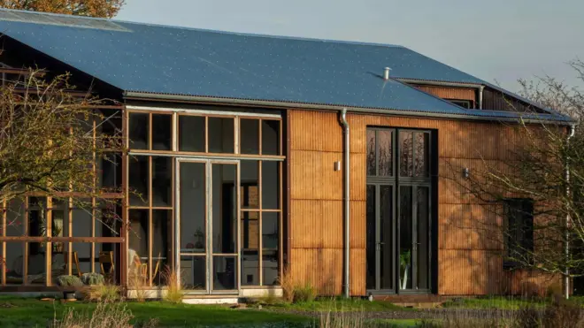 Casa em estilo celeiro, com grandes janelas de vidro e teto solar