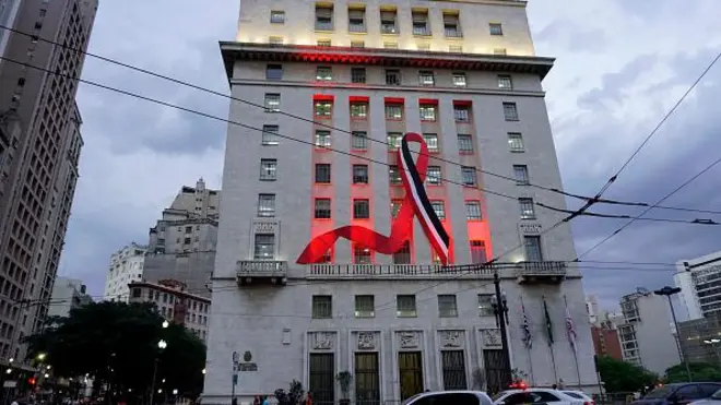 Grande laço nas cores preto, vermelho e branco estendido em prédio