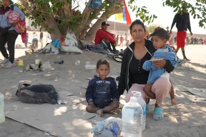 MiLexi Gomez agachada com os filhos em um campo com terra