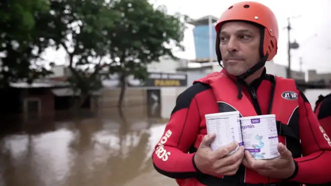 Bombeiro leva latas em barco em área alagada de Eldorado do Sul (RS) 