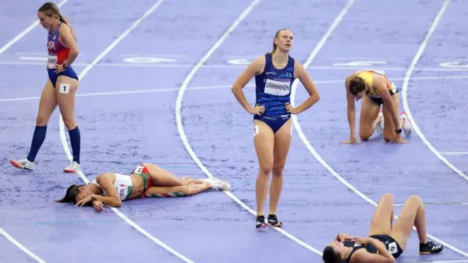 Atletas exaustas deitadas na pista após competir no heptatlo feminino nos Jogos Olímpicos de Paris 2024 