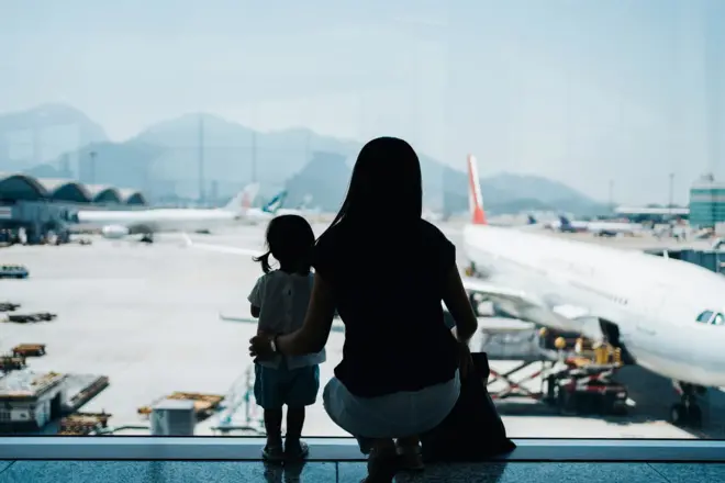 mulher e criança, de costas, em aeroporto