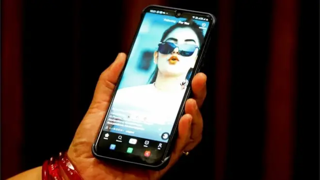 A woman watches a short video on the Chinese video-sharing app TikTok on her smartphone, in Bhopal, central India, 29 June 2020.