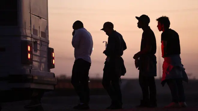 Fila de migrantes para entrar em ônibus no Arizona (EUA), depois de cruzarem a fronteira com o México