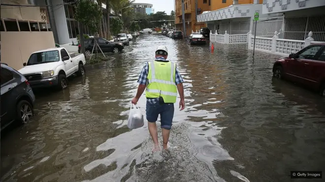 Homem anda em rua alagada