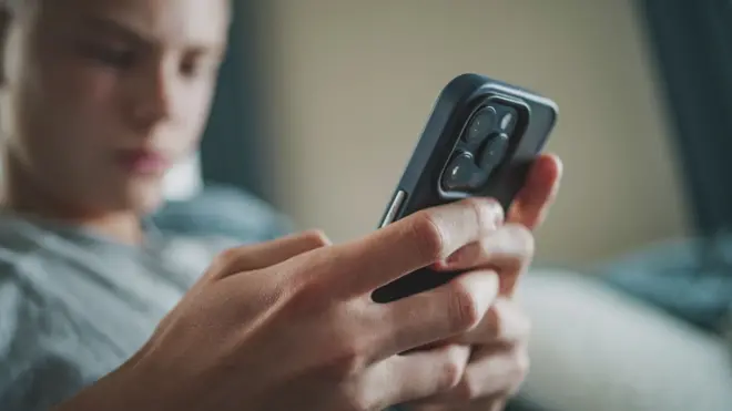 Stock image of a boy looking at a phone