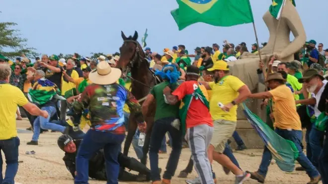 Policial militar é atacado por militantes bolsonaristas ao cair do cavalo na Praça dos Três Poderes, neste domingo.