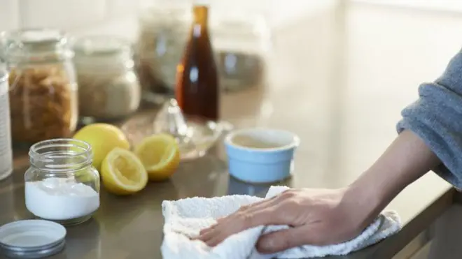 Mão de mulher limpando bancada da cozinha com pano