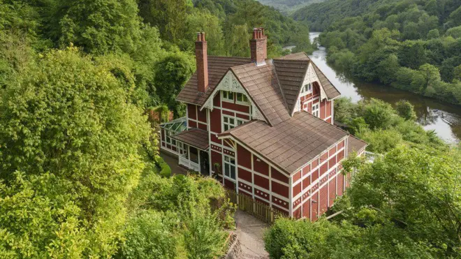 casa à beira da água em vista do alto, com árvores ao redor 