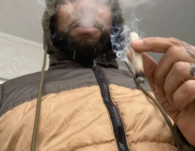 homem fumando o que parece ser um baseado, cigarro de maconha