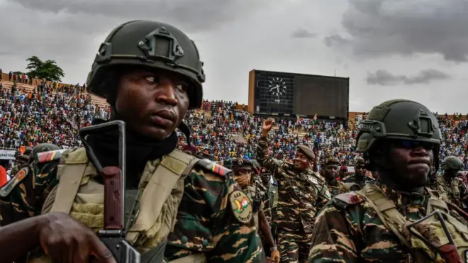 Flanqué de ses troupes, le chef du coup d'État du Niger, le général Abdourahamane Tchiani (au centre), salue les milliers de personnes présentes dans un stade de Niamey, le 26 juillet 2023. 