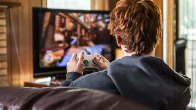 Adolescente jogando videogame em casa